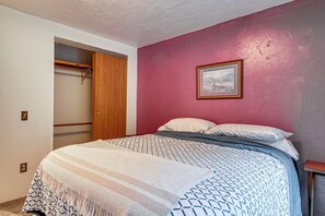 Ein Schlafzimmer mit einem Bett, einem Holzschrank, einem Bild an der Wand und einer roten Wand.