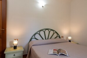 Ein Schlafzimmer mit einem Bett, zwei Nachttischlampen, einem Nachttisch mit Schublade und einem Buch auf dem Bett.