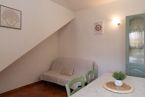 Ein gemütliches Zimmer mit einer gepolsterten Couch, einem kleinen Tisch mit einer Pflanze und einer Wandleuchte.