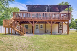 Ein zweistöckiges Haus mit einer Holzterrasse, einer überdachten Veranda und einer Garage.