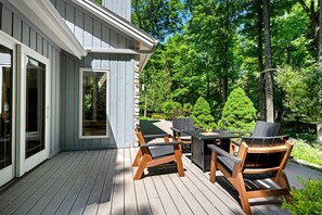 Eine Terrasse mit Holzbänken und einem Tisch, eine Steinmauer und eine Glastür.