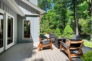 Eine Terrasse mit Holzbänken und einem Tisch, eine Steinmauer und eine Glastür.