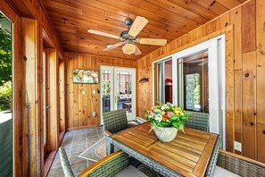 Ein Holzinterieur mit Esstisch, Stühlen, Deckenventilator und großem Fenster.