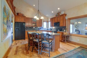 A kitchen with wooden cabinets, a refrigerator, a microwave, and a dining area with chairs. - Colorado Riverfront Escape! Fish, Hike & Relax (Pine)
