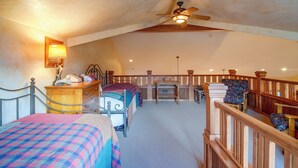 Ein Schlafzimmer mit zwei Betten, einem Schreibtisch, einem Stuhl, einem Deckenventilator und einer Treppe.