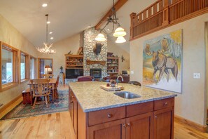 A spacious kitchen with a large island, wooden cabinetry, and a stone fireplace. - Colorado Riverfront Escape! Fish, Hike & Relax (Pine)