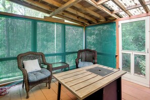 A covered outdoor seating area with wicker chairs and a table, surrounded by green mesh screens and wooden beams. - Access to Centerville's Resident Beaches! Cozy Gem (Centerville)