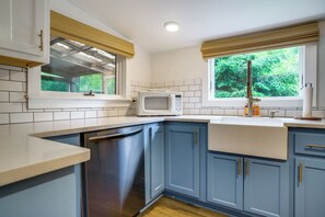 Una cocina equipada con lavavajillas, microondas y ventana con vistas a la vegetación.