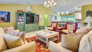 Ein Wohnzimmer mit Fernseher, Bücherregalen, einem Couchtisch und einem Essbereich mit Stühlen.