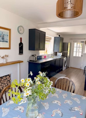 A kitchen with dark cabinets, a microwave, and a washing machine. - Garden Cottage on the edge of Oxford (Kennington)