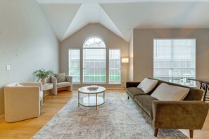 A living room with a high ceiling, a round coffee table, a sofa, and a chair. - 4 Mi to Toyota Stadium! Family Haven w/ Pool Oasis (Frisco)