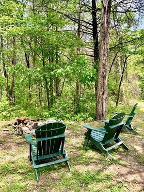 Two green Adirondack chairs in a forested area with a pile of firewood. - Real Private Cabin with Idyllic for a Secluded Romantic Getaway in Arkansas (Eureka Springs)