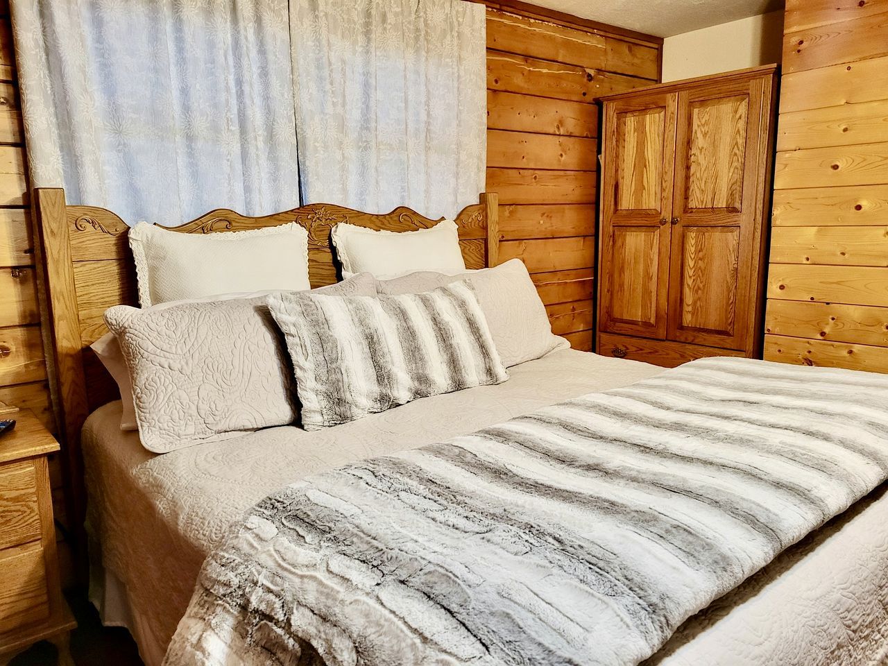 Een bed met een gestreept dekbed, een houten hoofdbord en twee kussens.