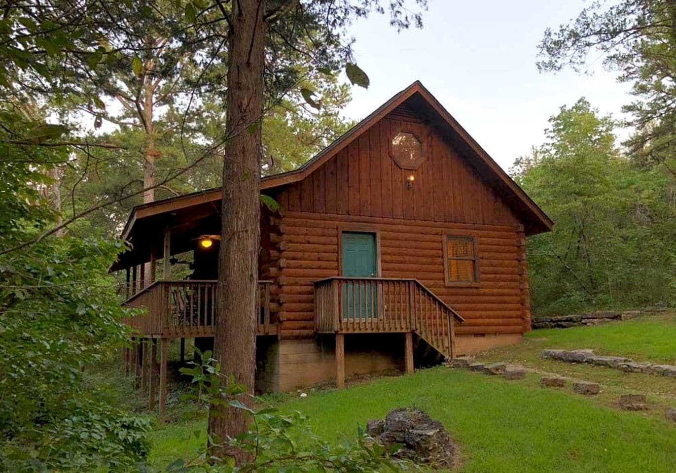 Une cabane en bois dotée d’un balcon, entourée d’arbres.