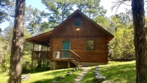 Eine Blockhütte mit Balkon und einer Treppe, die zum Eingang führt.