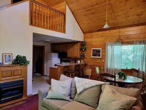 A cozy cabin interior with a living room, dining area, kitchen, and a loft bedroom. - Real Private Cabin with Idyllic for a Secluded Romantic Getaway in Arkansas (Eureka Springs)