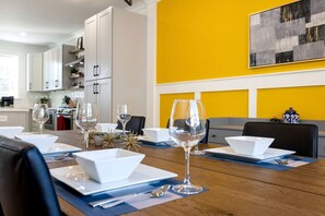 Comedor con una mesa de madera dispuesta para una comida, platos blancos y copas de vino.
