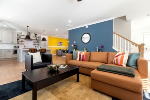 A modern living room with a sofa, coffee table, and a kitchen in the background. - Luminous Urban Vacation Rental Haven near Catawba River in North Carolina (Charlotte)