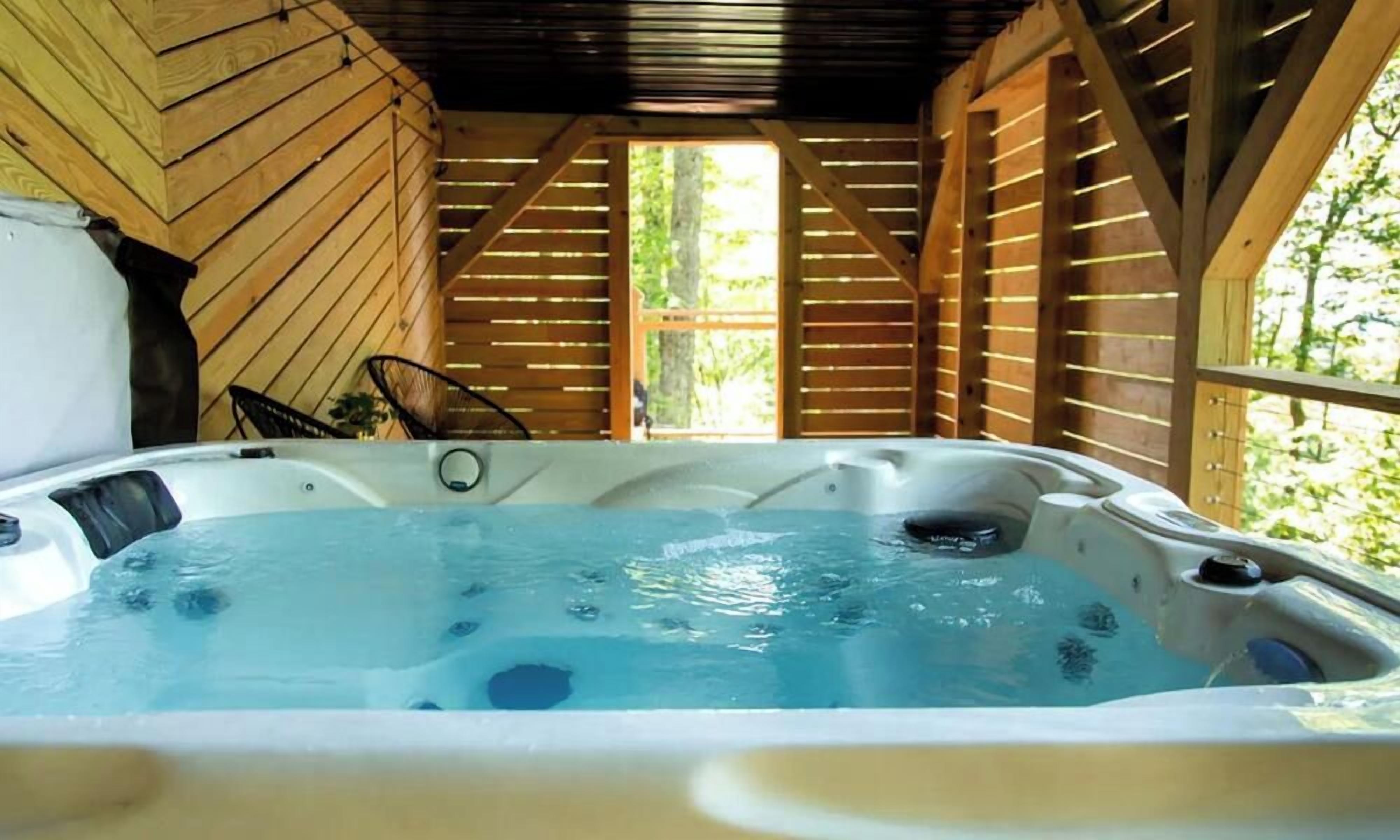 Een hottub in een houten blokhut met uitzicht op groen.