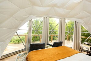 Un hébergement sous tente comprenant un lit, deux chaises et une table.