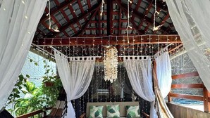 Una habitación acogedora y rústica con una hamaca, un rincón de asientos mullidos y una lámpara colgante.