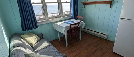 A compact room with a bed, a small table, a TV, and a refrigerator.