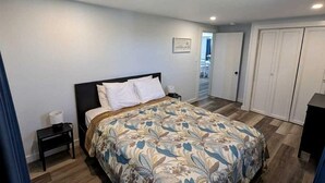A bedroom with a bed, a nightstand, a wardrobe, and a door leading to another room. - Cozy Coastal Cottage Right on the Water’s Edge in North Truro, Massachusetts (North Truro)