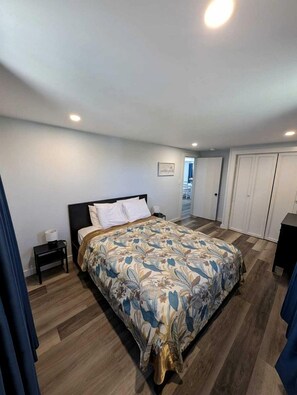 A bedroom with a bed, a nightstand, a wardrobe, and a door leading to another room. - Cozy Coastal Cottage Right on the Water’s Edge in North Truro, Massachusetts (North Truro)