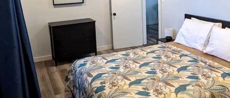 Un dormitorio con una cama, un aparador, una puerta y un cuadro en la pared.