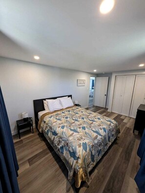 Un dormitorio con cama, mesita de noche, armario y puerta que da a otra habitación.