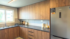 Eine moderne Küche mit Holzausstattung, einem Edelstahlkühlschrank und einem Fenster mit Tageslicht.