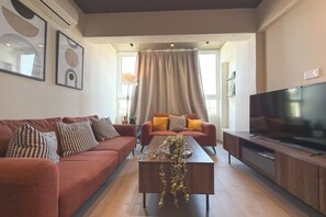 A modern living room with a sofa, coffee table, and TV stand. - Nicosia 2BR Apt with AC & Washer (Metehan)