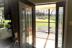 A sliding glass door leading to a deck with a view of a landscaped yard.