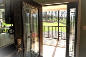 Puerta corrediza de vidrio que da a una terraza con vista a un jardín ajardinado.