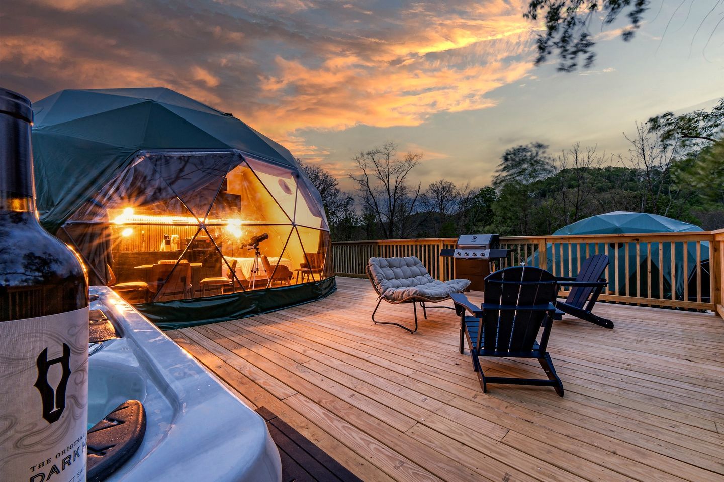 A wooden deck with a tent, outdoor furniture, and a grill.