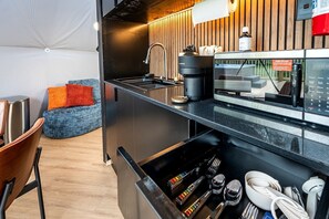 A modern kitchen with a coffee machine, sink, and wooden accents.