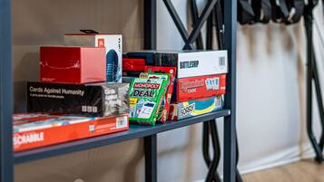 Une étagère contenant divers jeux de société, notamment Cards Against Humanity, Monopoly Deal et Battleship.