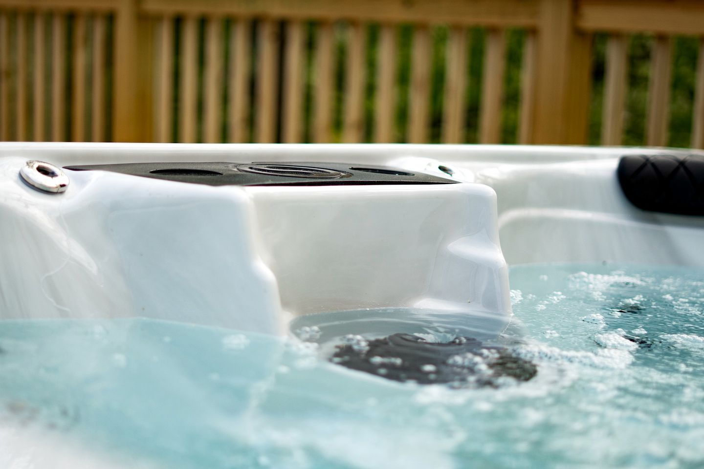 Un jacuzzi con panel de control, rodeado por una cerca de madera.