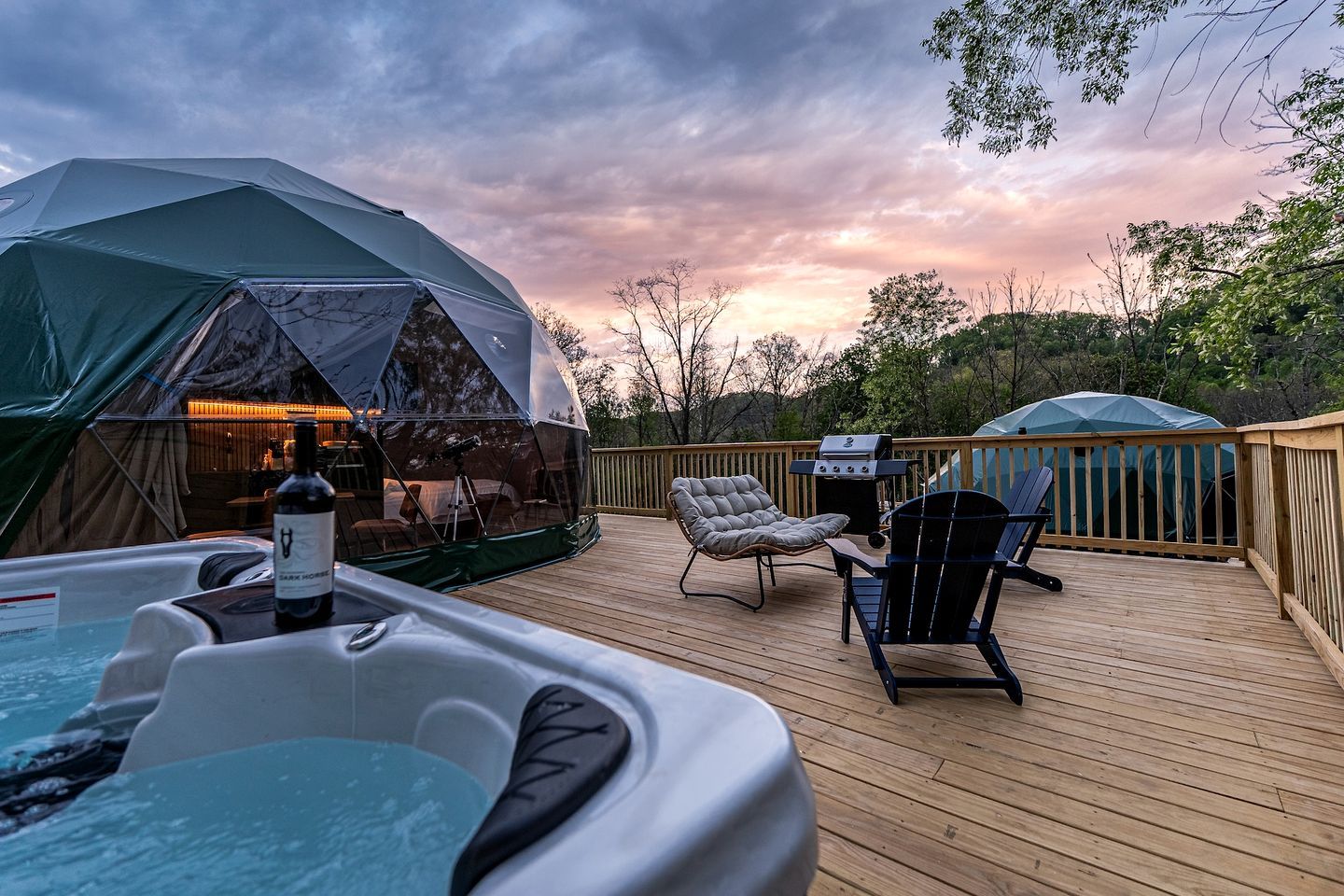 A wooden deck with a hot tub, lounge chairs, and a tent.