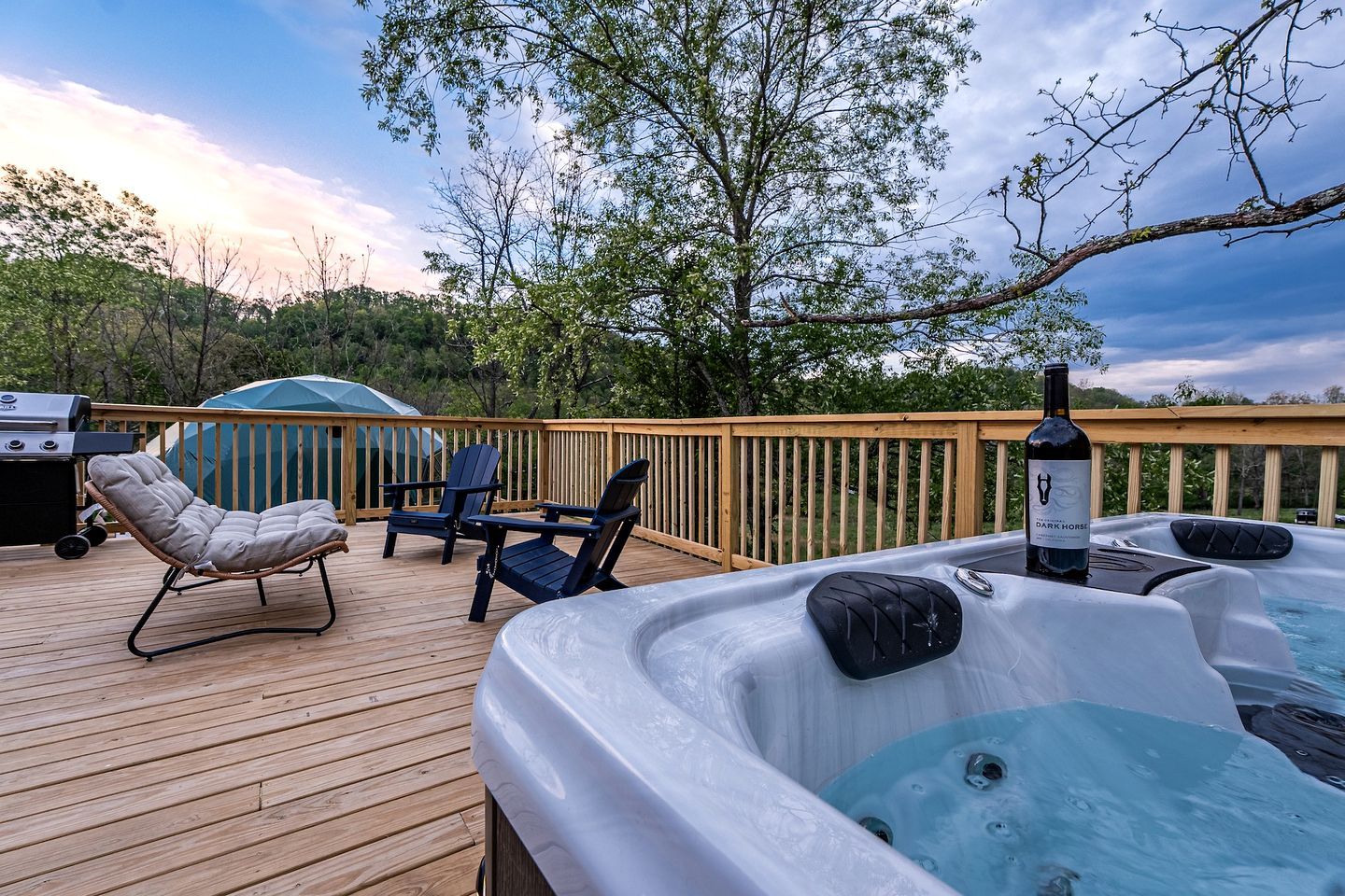 A deck with hot tubs, chairs, and a grill.