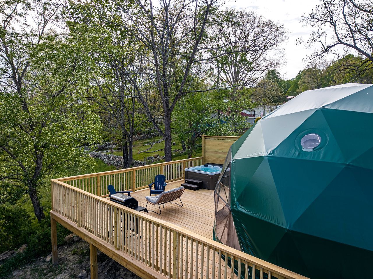 A deck with a hot tub, outdoor seating, and a large umbrella.