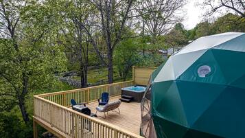 A deck with a hot tub, outdoor seating, and a large umbrella.