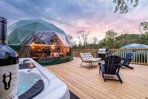 Ein überdachter Außenbereich mit Whirlpool, Liegestühlen und Grill.