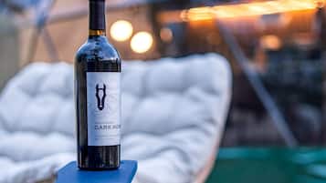 Una botella de vino sobre una mesa con una silla blanca acolchada al fondo.