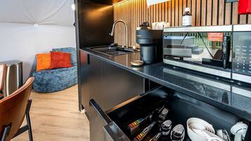 A modern kitchen with a coffee machine, sink, and wooden accents.
