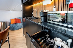 A modern kitchen with a coffee machine, sink, and wooden accents. - Geodesic Dome Retreat with Hot Tub & Fire Pit in Bluefield, West Virginia (Blueflield)
