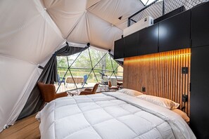 A tent-style room with a bed, seating area, and a view of the outdoors.