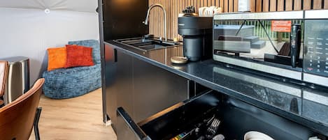 Une cuisine moderne dotée d’une machine à café, d’un évier et d’éléments décoratifs en bois.