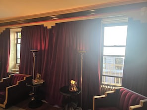 A room with a large window, a radiator, a floor lamp, a chair, and a small table with books and a lamp. - Fabulous Art deco Manhattan pad! Stylish, cozy 1 bedroom apt near everything (New York)