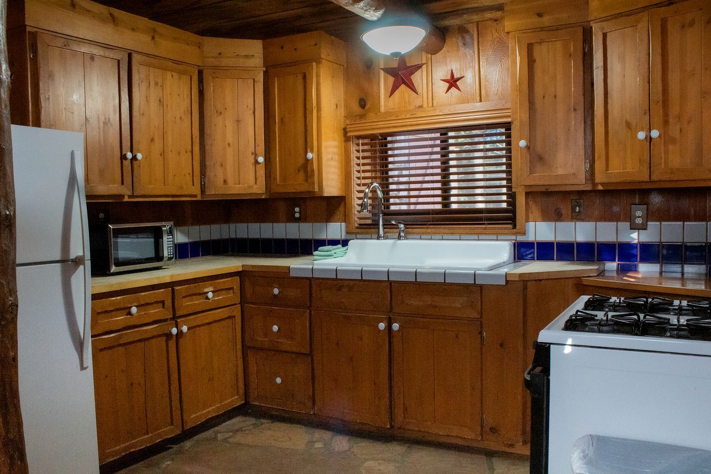 Una cocina con armarios de madera, un microondas, un lavamanos y una estufa.